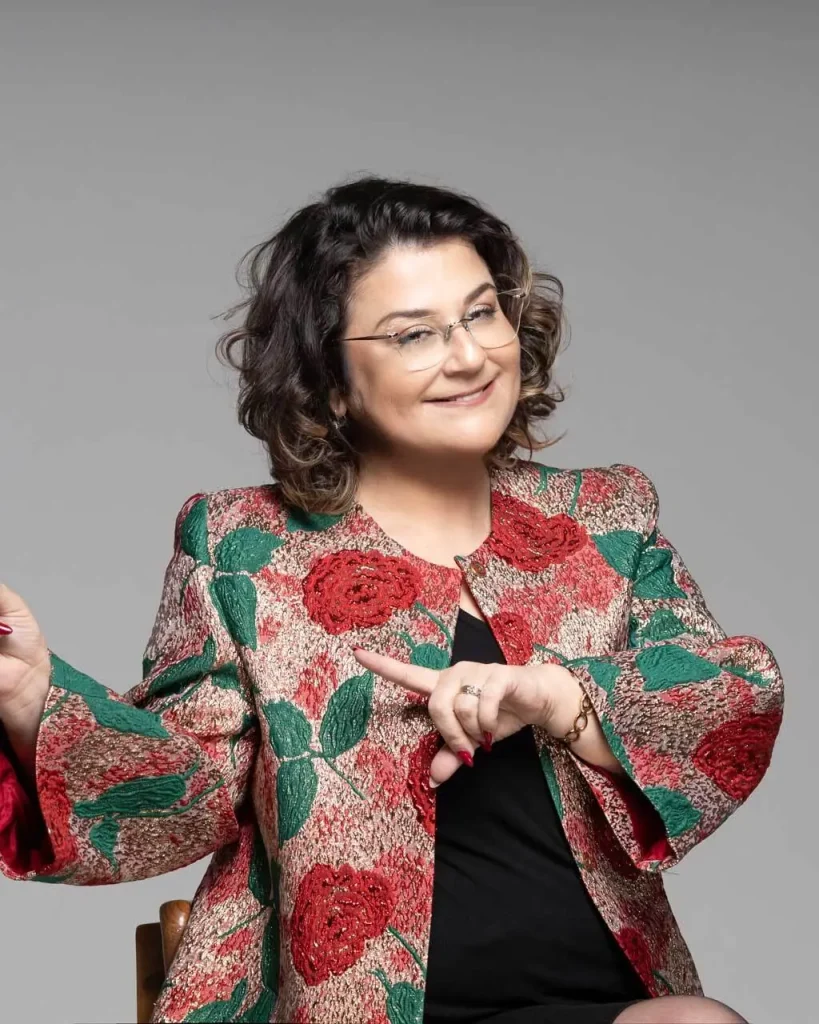 Dr. Menekşe Ahbab, çiçek desenli ceketle bir noktayı işaret ederken