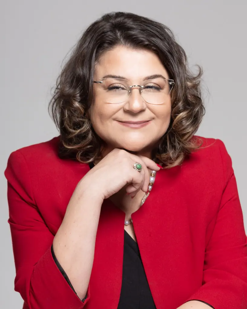 Dr. Menekşe Ahbab, kırmızı ceketle gülümserken